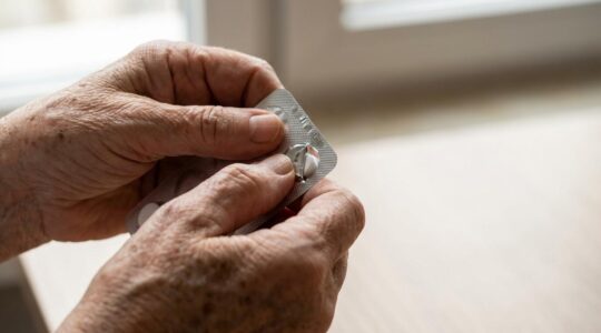 Main de personne âgée manipulant un blister pharmaceutique sécurisé avec témoin d'inviolabilité visible